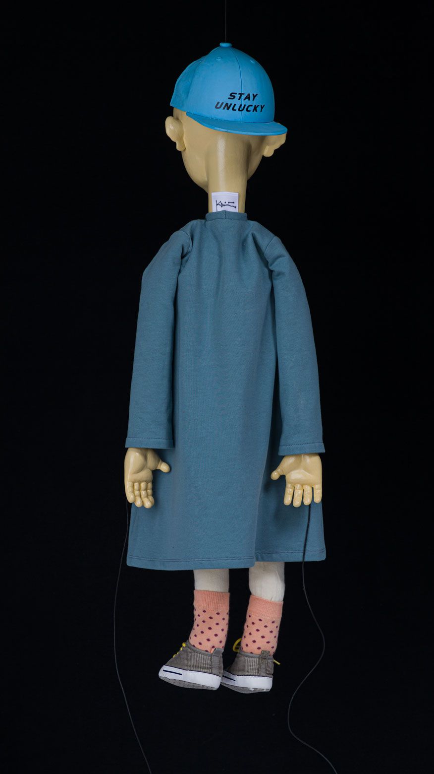 Bagside af skulpturen Stay Unlucky med blÃ¥ kasket og kunstnerens mÃ¦rkat.